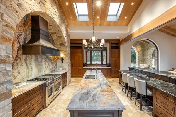 a large kitchen with kitchen island a stove a sink a dining table and chairs with wooden floor