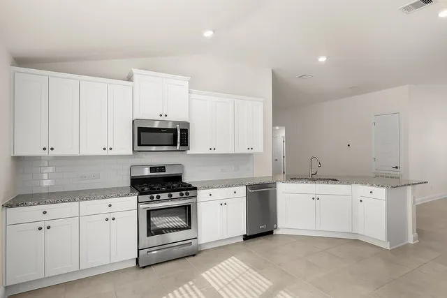 a kitchen with granite countertop white cabinets and stainless steel appliances