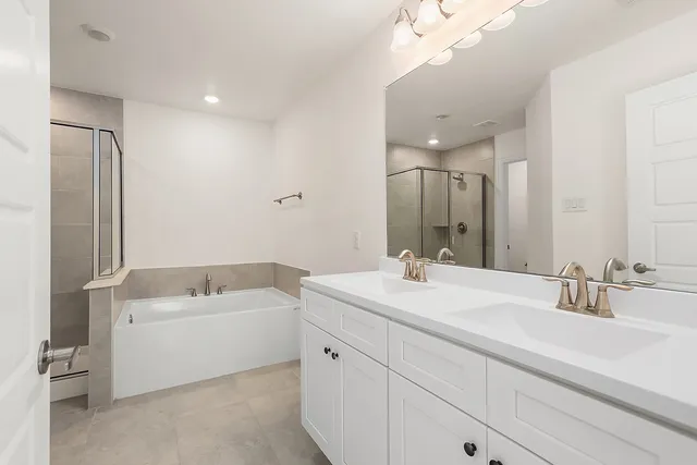a bathroom with a double vanity sink mirror and bathtub