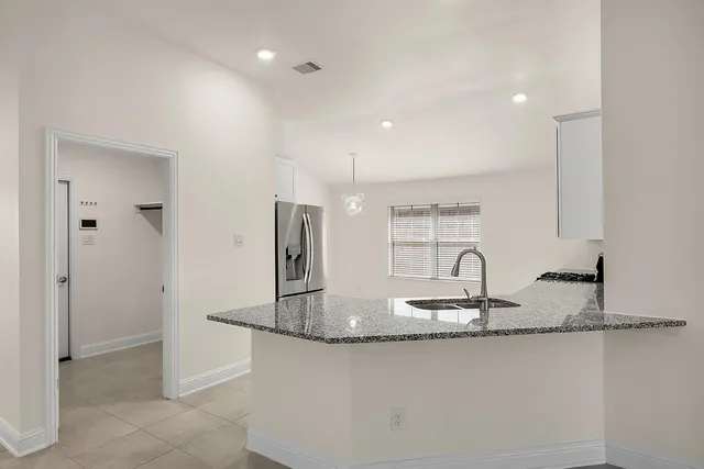 a kitchen with kitchen island granite countertop a sink and a refrigerator
