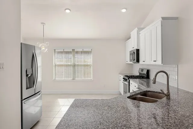 a kitchen with stainless steel appliances granite countertop a sink and a refrigerator