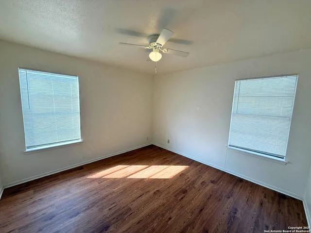 an empty room with wooden floor and windows