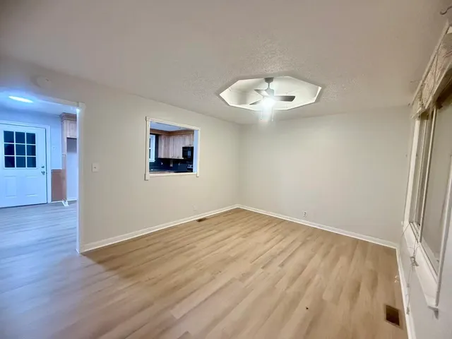 an empty room with wooden floor and windows