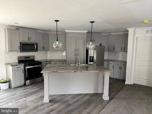 a kitchen with kitchen island a counter top space appliances and cabinets