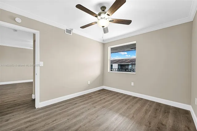 a view of a hallway with wooden floor and a bathroom