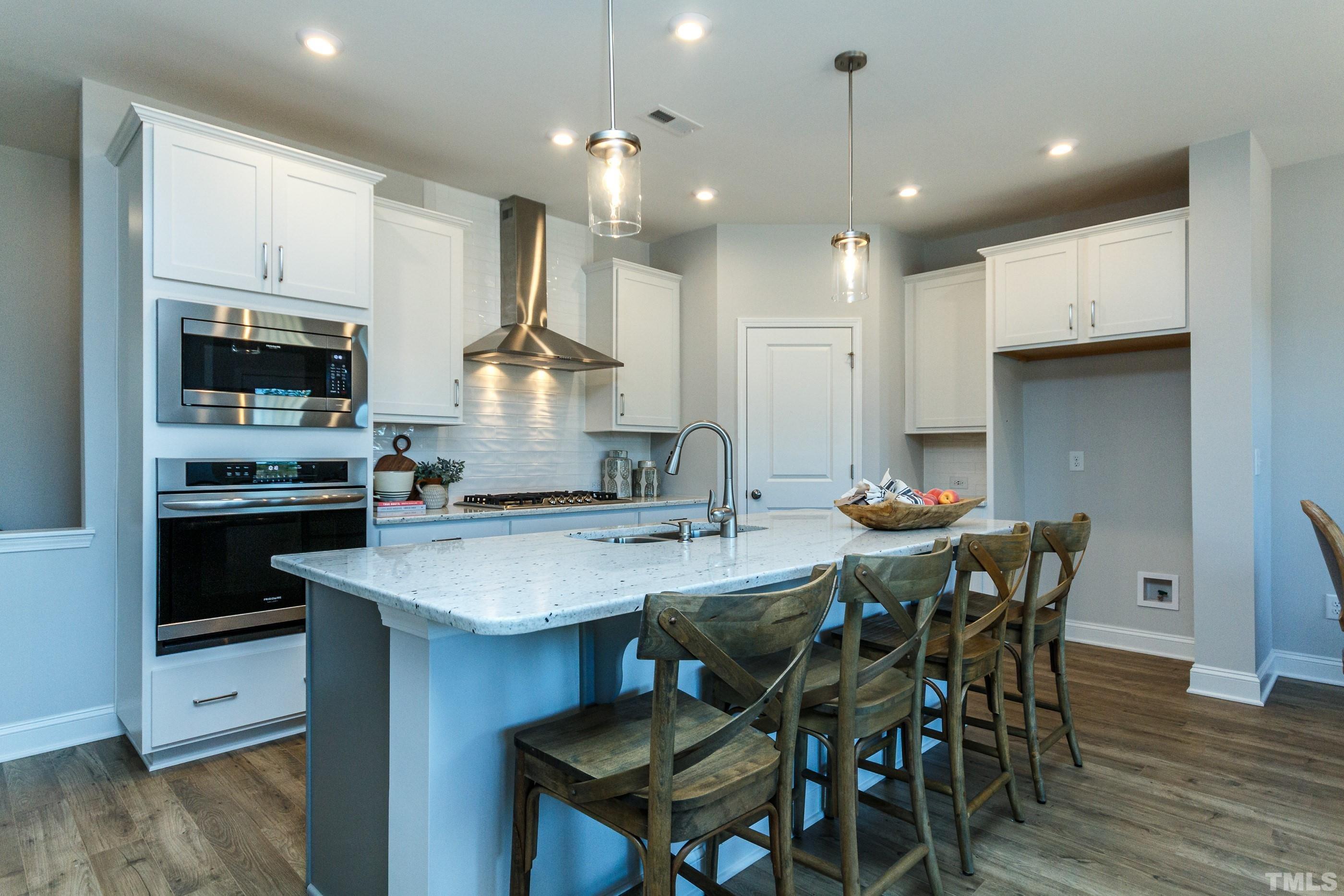 a kitchen with stainless steel appliances kitchen island granite countertop a sink a stove a dining table and chairs