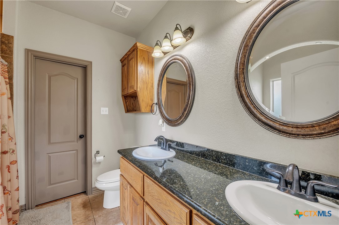4945 Water Works Road Belton, TX 76513 - Photo 13 of 36 a bathroom with a granite countertop double vanity sink and a mirror