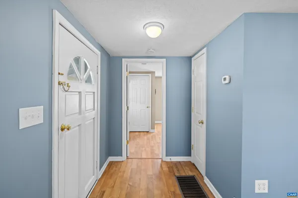 a view of an empty room with window and wooden floor