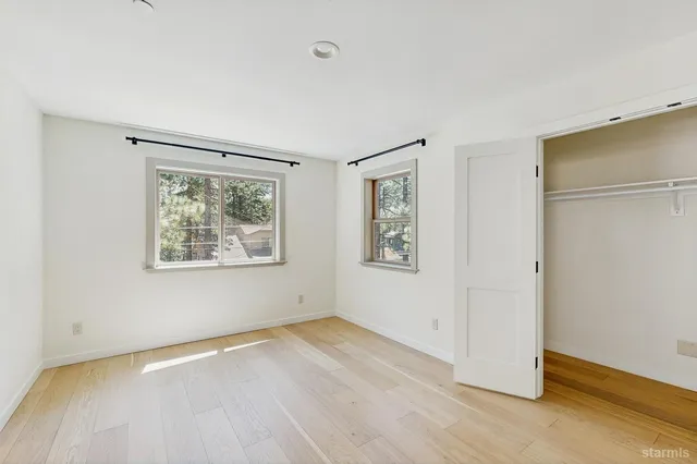 a view of an empty room with a window and wooden floor