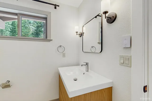 a bathroom with a sink and mirror with window