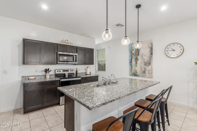 a kitchen with granite countertop a table chairs sink and microwave