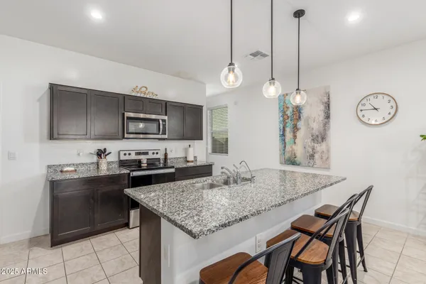 a kitchen with granite countertop a table chairs sink and microwave