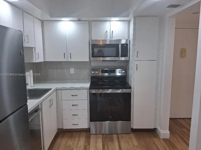 a kitchen with white cabinets and stainless steel appliances