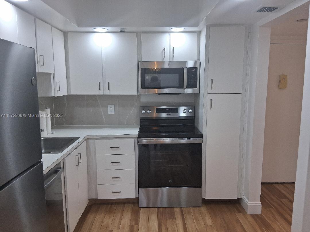 1000 St Charles Place, Unit L20 Pembroke Pines, FL 33026 - Photo 6 of 23 a kitchen with white cabinets and stainless steel appliances