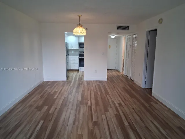 a view of empty room with wooden floor