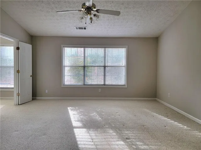 an empty room with windows and fan