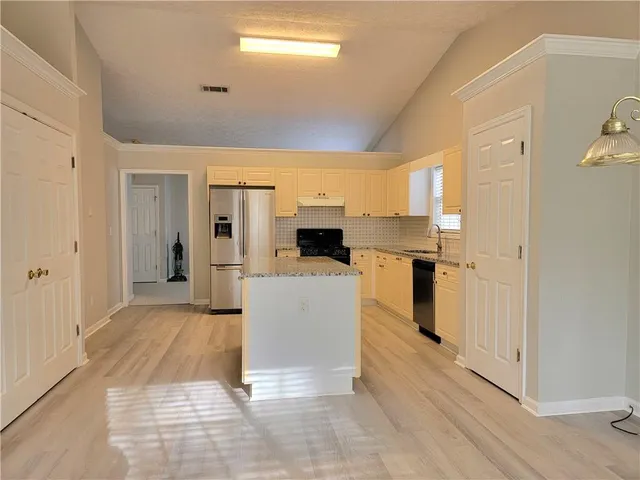 a living room with stainless steel appliances kitchen island granite countertop a refrigerator and a stove top oven