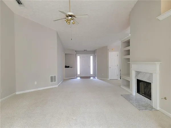 an empty room with windows and fireplace