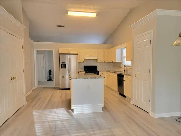 a view of a kitchen with a sink and dishwasher a refrigerator with wooden floor