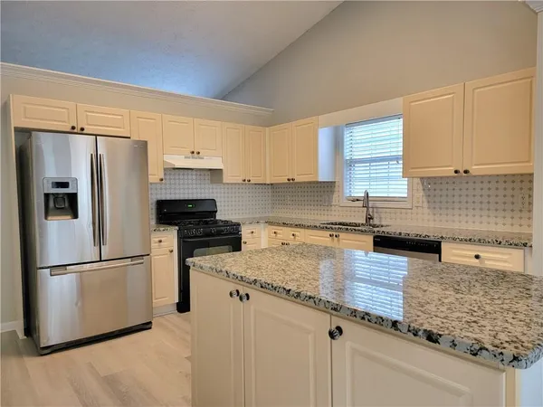 a kitchen with granite countertop a refrigerator stove and sink