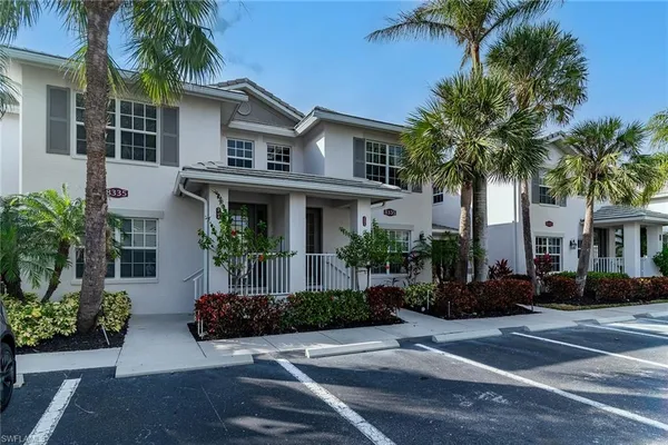 front view of a house with a yard and palm trees
