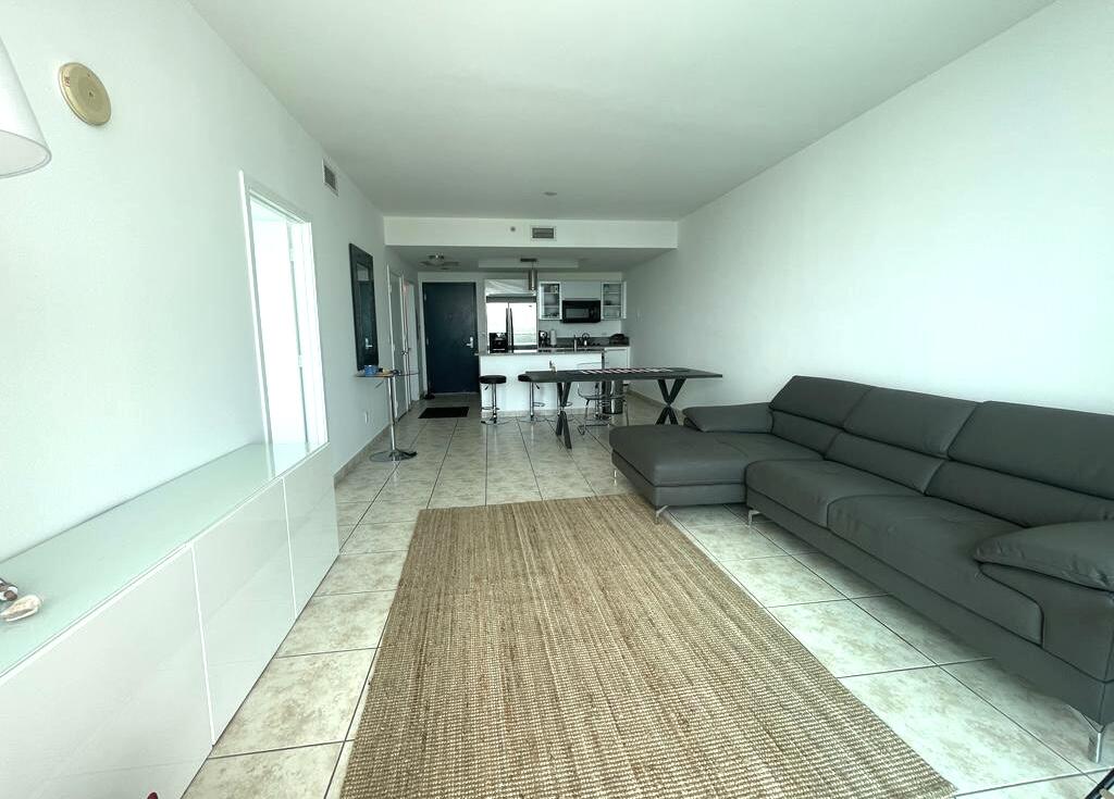 888 Biscayne Boulevard, Unit 811 Miami, FL 33132 - Photo 8 of 33 a living room with couches and kitchen view with wooden floor