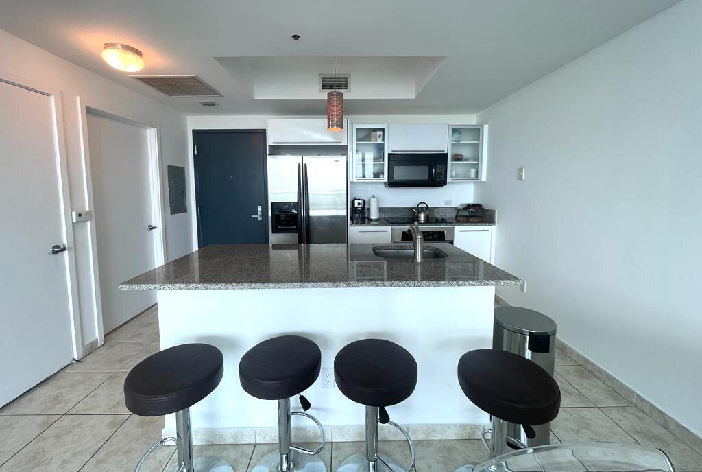 888 Biscayne Boulevard, Unit 811 Miami, FL 33132 - Photo 9 of 33 a kitchen with stainless steel appliances granite countertop a dining table chairs and a refrigerator