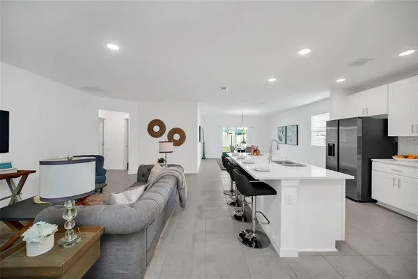 a living room with furniture a refrigerator and kitchen view