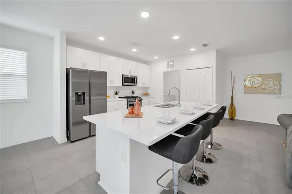 a kitchen with stainless steel appliances kitchen island granite countertop a sink a refrigerator and a stove