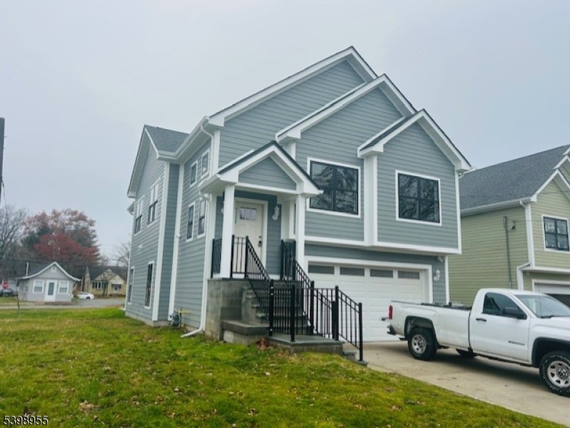 a view of a white house next to a big yard and large trees