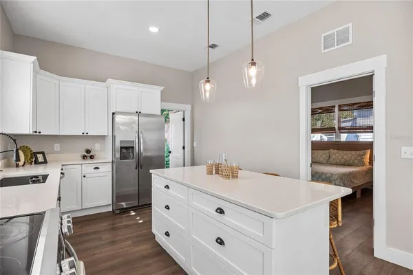 a kitchen with a refrigerator a sink dishwasher and white cabinets with wooden floor