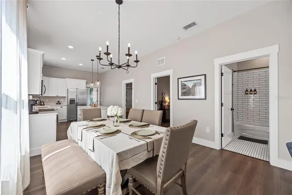 a view of a dining room and livingroom with furniture wooden floor a chandelier