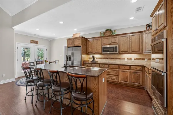 a kitchen with stainless steel appliances granite countertop a stove a sink dishwasher a dining table and chairs with wooden floor
