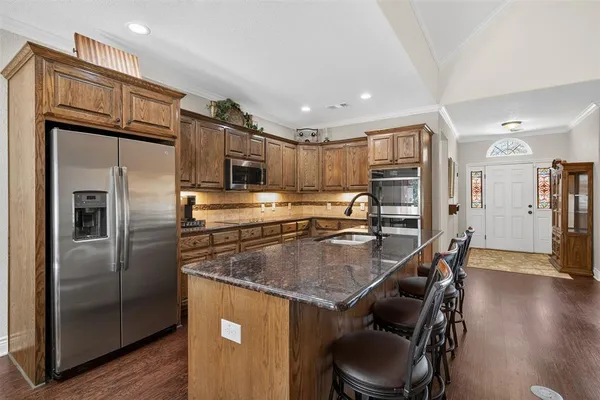 a kitchen with stainless steel appliances granite countertop a refrigerator a stove and a sink