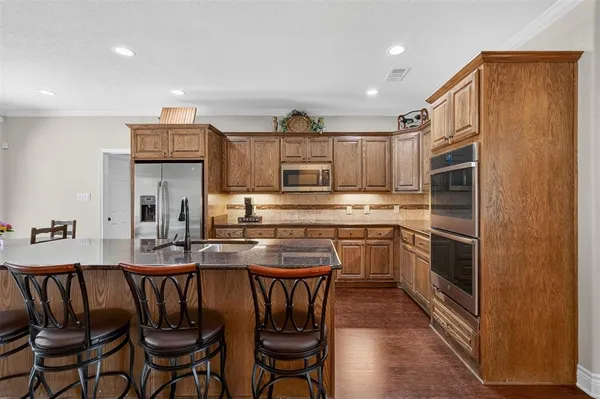 a kitchen with kitchen island granite countertop wooden cabinets and stainless steel appliances