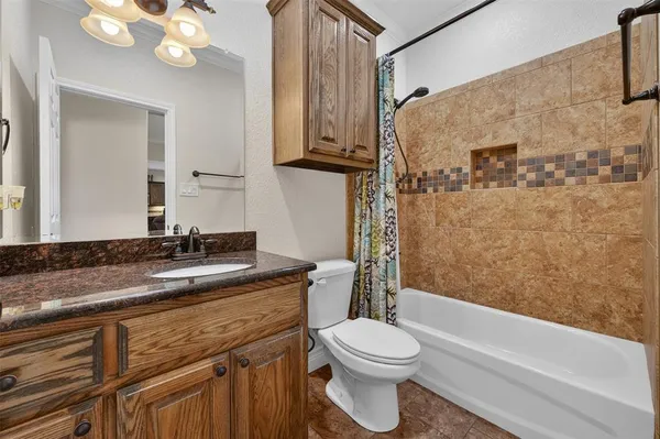 a bathroom with a granite countertop toilet sink and mirror