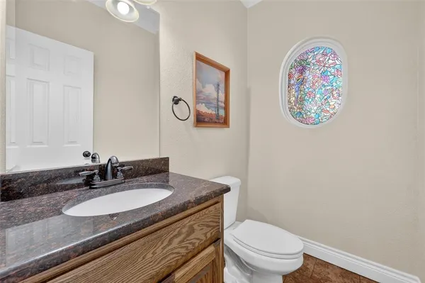 a bathroom with a granite countertop toilet a sink and a mirror