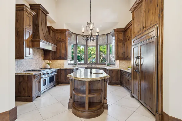 a kitchen with stainless steel appliances granite countertop a sink a stove and a wooden cabinets