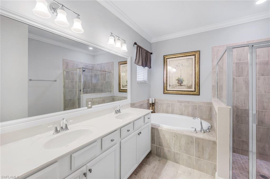 4244 Raffia Palm Circle Naples, FL 34119 - Photo 19 of 38 a bathroom with a tub double vanity sink and mirror