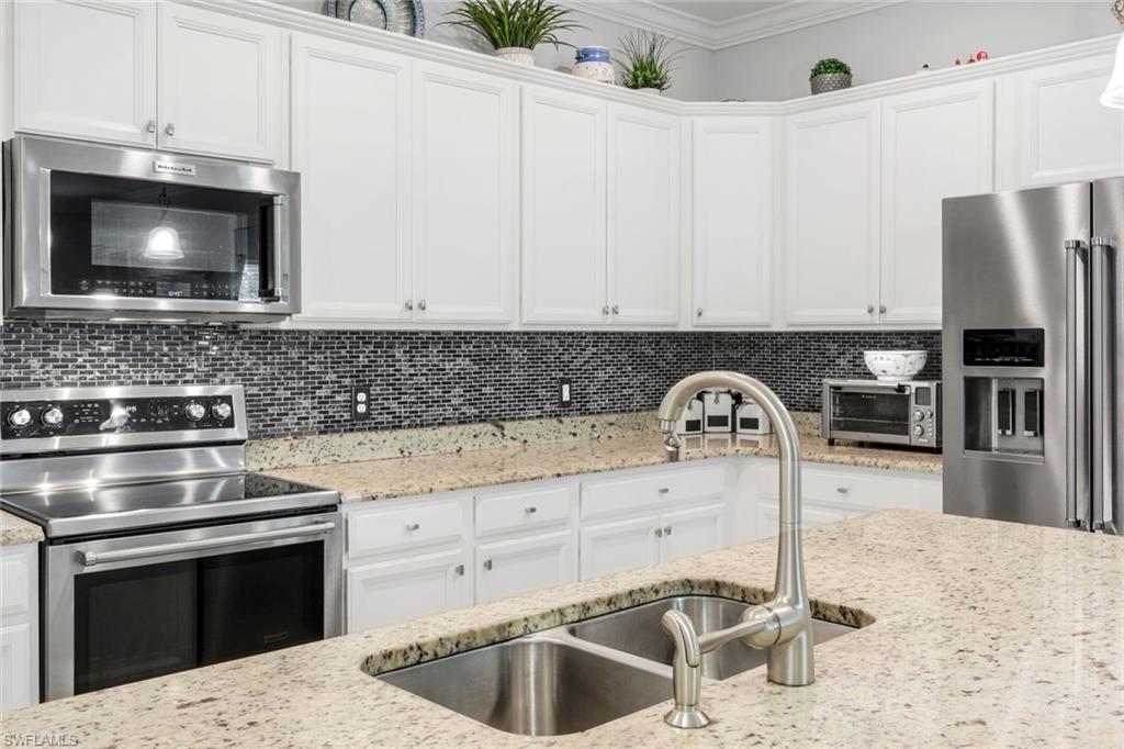 4244 Raffia Palm Circle Naples, FL 34119 - Photo 6 of 38 a kitchen with a stove microwave and refrigerator