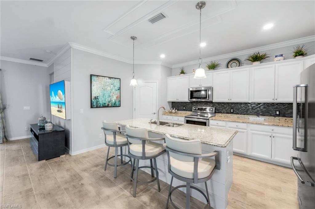 4244 Raffia Palm Circle Naples, FL 34119 - Photo 7 of 38 a kitchen with a dining table chairs and white cabinets