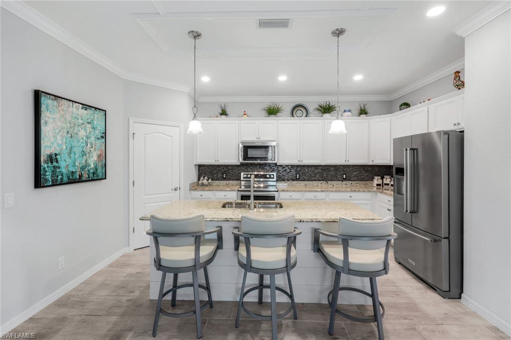 4244 Raffia Palm Circle Naples, FL 34119 - Photo 9 of 38 a kitchen with kitchen island wooden cabinets and refrigerator