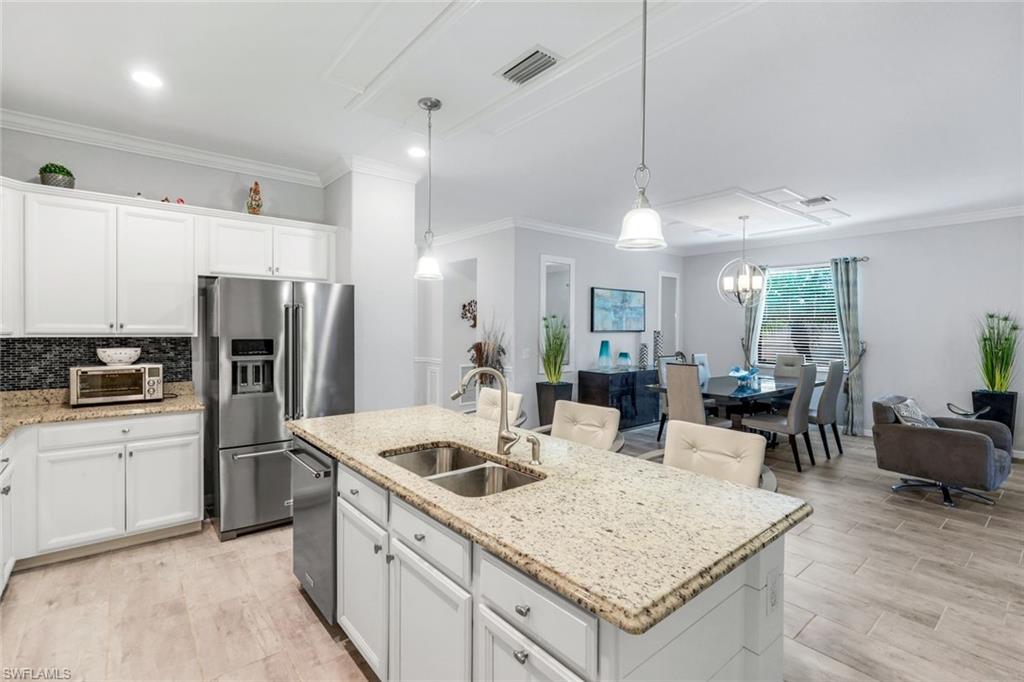 4244 Raffia Palm Circle Naples, FL 34119 - Photo 10 of 38 a kitchen with a refrigerator a sink dishwasher a oven with white cabinets and wooden floor
