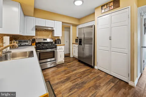 a kitchen with granite countertop a refrigerator and a stove top oven