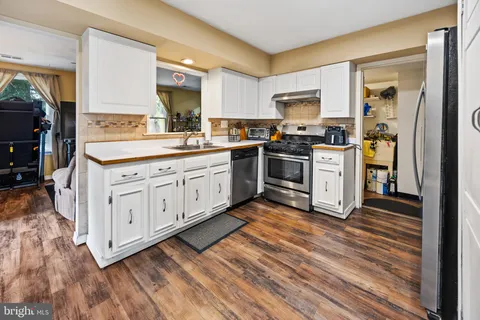 a kitchen with stainless steel appliances granite countertop a stove a sink and a refrigerator