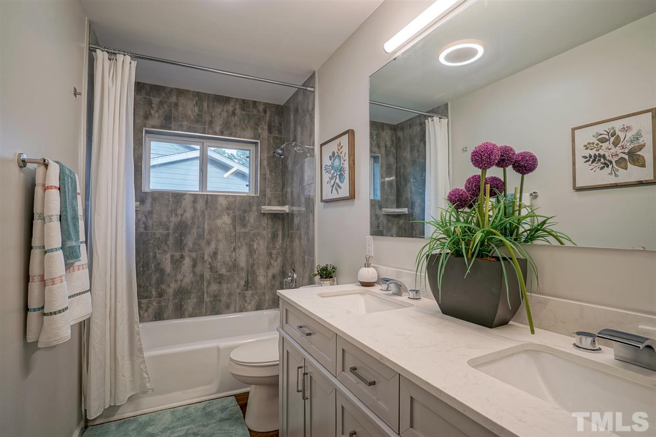 1105 Paddock Drive Raleigh, NC 27609 - Photo 20 of 30 a bathroom with a sink a large mirror and a toilet
