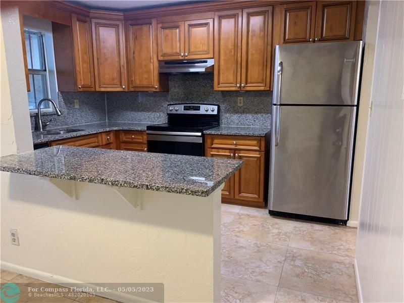 a kitchen with granite countertop a refrigerator a stove a sink and dishwasher