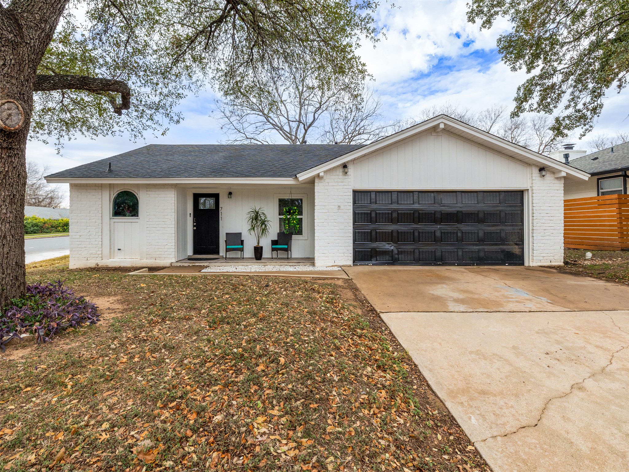 Single story home with brick siding, covered porch, concrete driveway, roof with shingles, and a garage