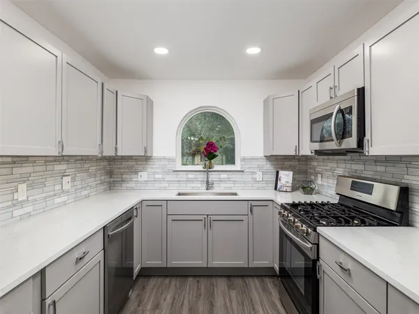 a kitchen with stainless steel appliances granite countertop a sink and cabinets with wooden floor