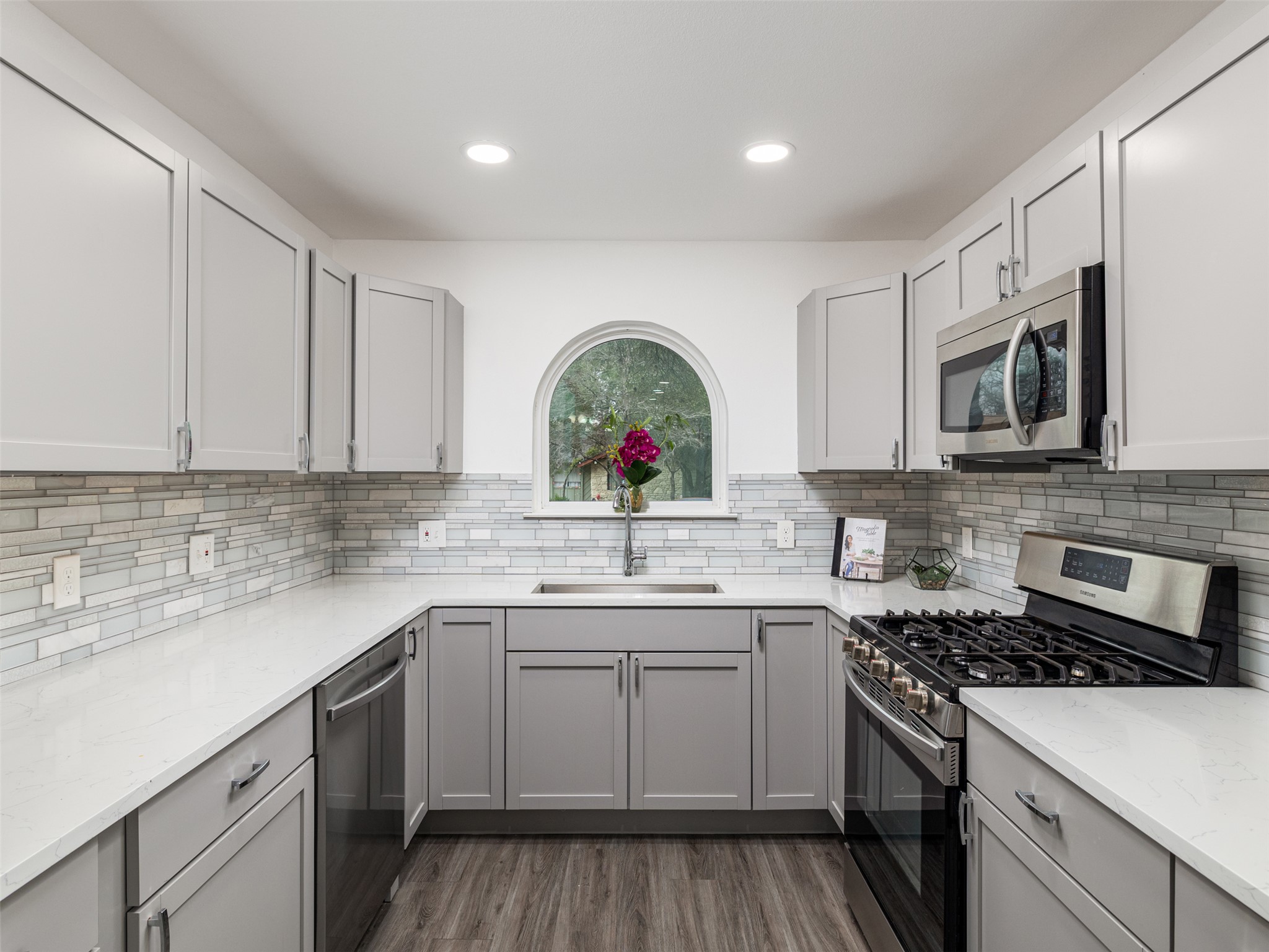 711 Buckingham Place Austin, TX 78745 - Photo 9 of 25 Kitchen with gray cabinetry, stainless steel appliances, light stone counters, light wood-type flooring, and recessed lighting